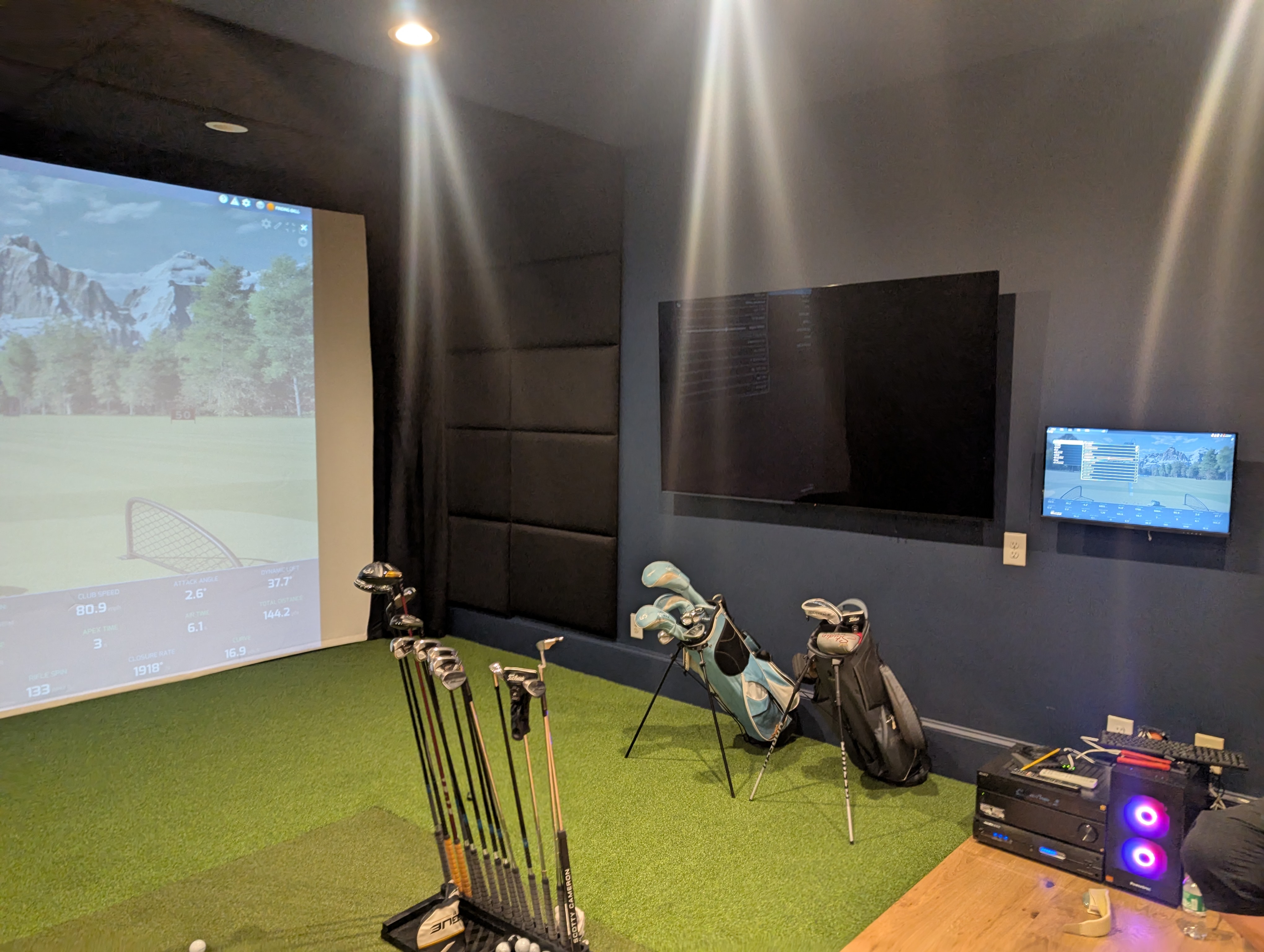 Integrated golf simulator room with projection screen, control displays and equipment